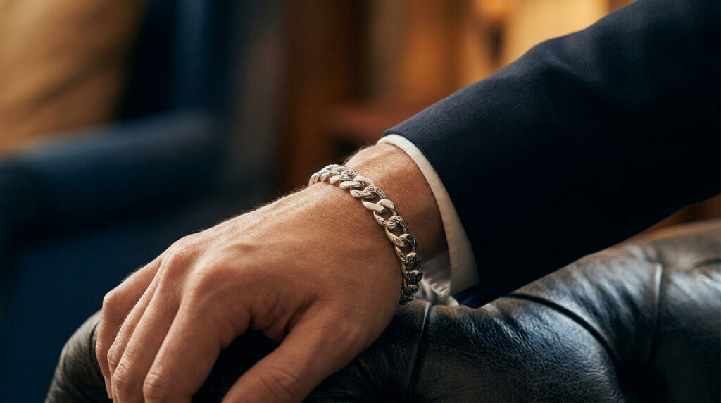 Sublimez votre style avec un bracelet homme argent Gros plan sur un poignet d'homme portant un bracelet en argent massif gravé, vêtu d'une veste de costume bleu marine.